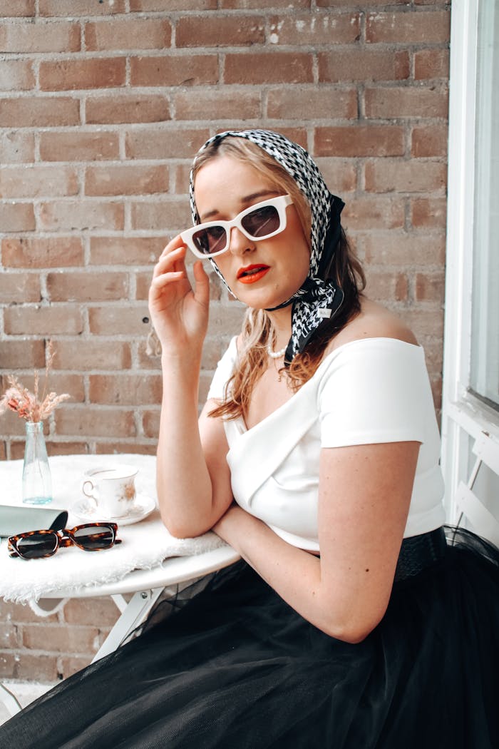 Chic woman in sunglasses and headscarf enjoying a sunny day outdoors.